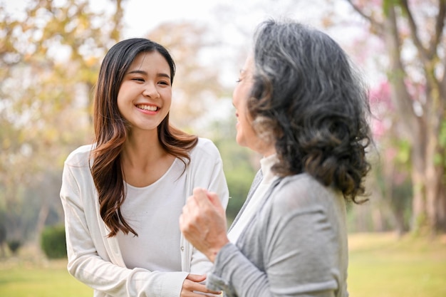 Encantadora y feliz nieta asiática pasando tiempo con su abuela en el parque verde