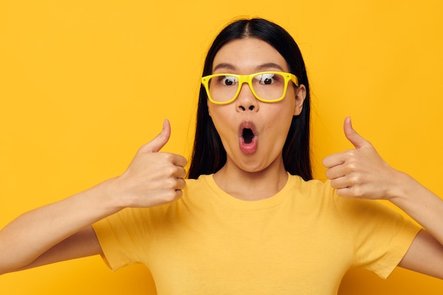 Encantadora jovem asiática em camisetas amarelas com óculos posando moda Estilo de vida inalterado
