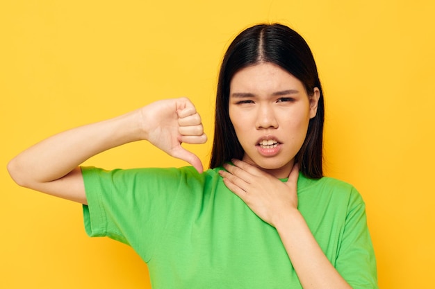 Encantadora jovem asiática em gestos de camiseta verde com as mãos emoções modelo de estúdio inalterado