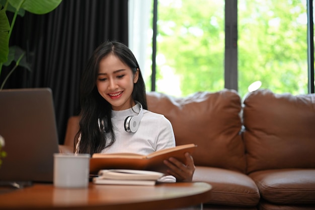 Encantadora jovem asiática lendo um livro em casa