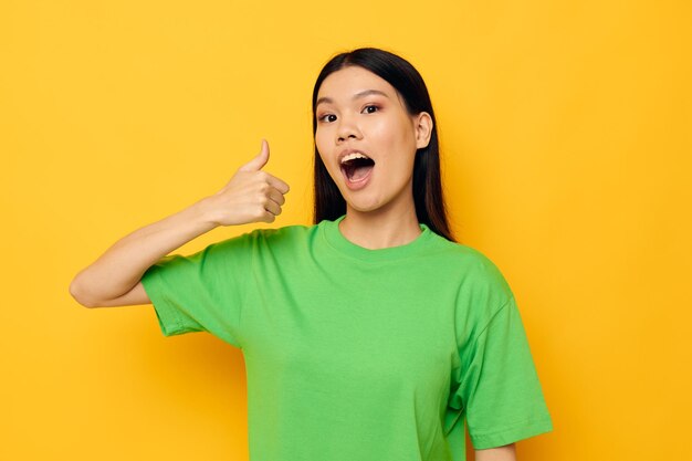 Encantadora jovem asiática posando em camiseta verde emoções copyspace fundo isolado inalterado