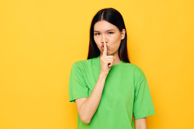 Encantadora jovem asiática posando em camiseta verde emoções copyspace fundo isolado inalterado