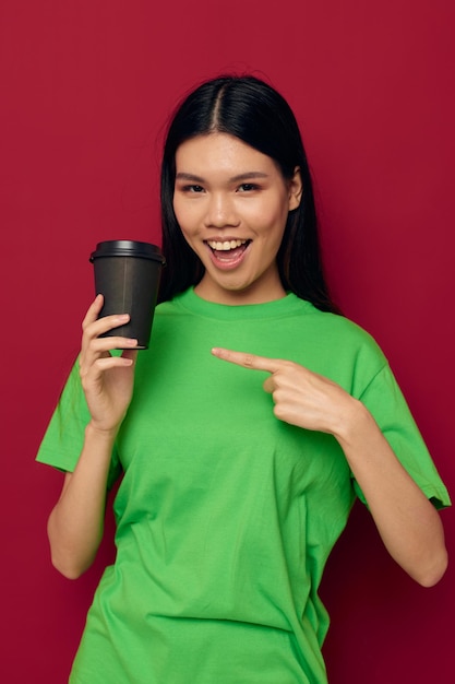 Encantadora jovem asiática posando em um modelo de estúdio de óculos pretos descartáveis de camiseta verde inalterado