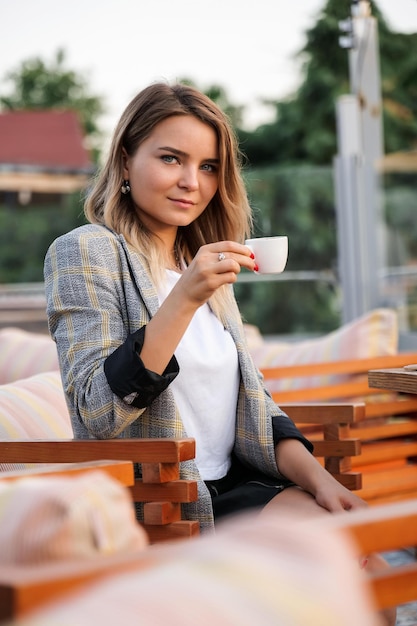 Encantadora jovem empresária sentada à mesa com uma xícara de café
