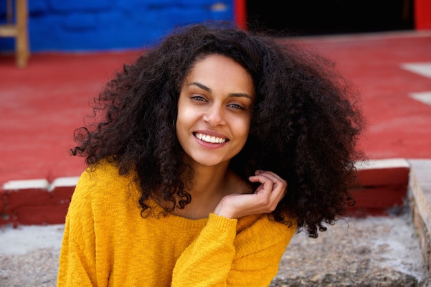 Foto encantadora jovem mulher africana sentado ao ar livre