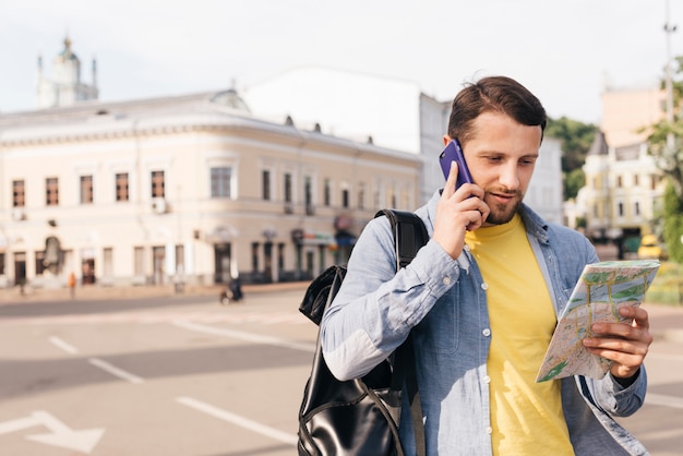 Encantadora jovem olhando mapa enquanto fala no celular na rua