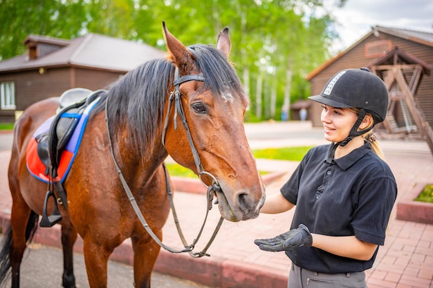 Encantadora joven con casco acariciando a su caballo marrón