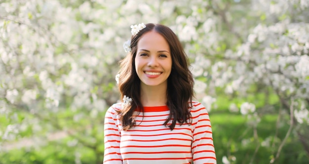 encantadora joven feliz sonriente en el jardín en flor de primavera con flores blancas en los árboles en el parque