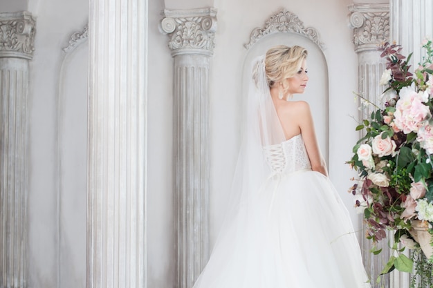 Encantadora joven novia en lujoso vestido de novia. Chica guapa, estudio fotográfico