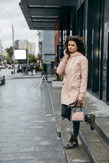 Encantadora joven rizada caminando por la calle