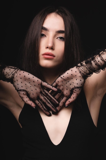 Foto encantadora joven sobre un fondo negro retrato de moda de una chica con guantes transparentes