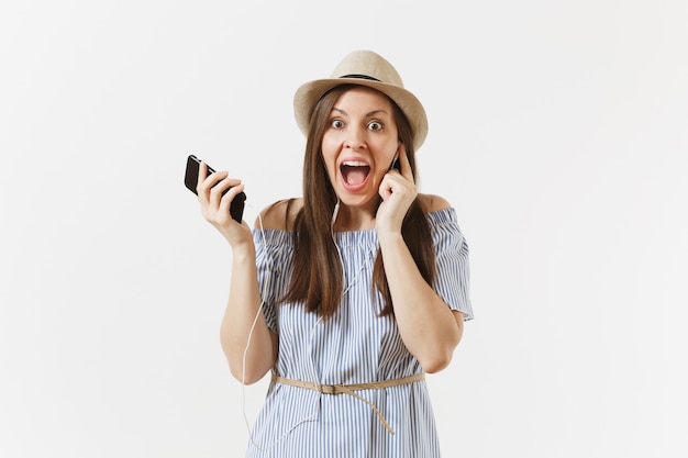 Encantadora joven vestida, sombrero escuchando música en auriculares en el teléfono móvil, disfrutar, relajarse aislado sobre fondo blanco. Gente, emociones sinceras, concepto de estilo de vida. Área de publicidad. Copie el espacio.