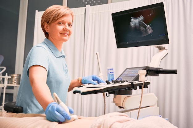 Foto encantadora médica fazendo exame de ultrassom na clínica