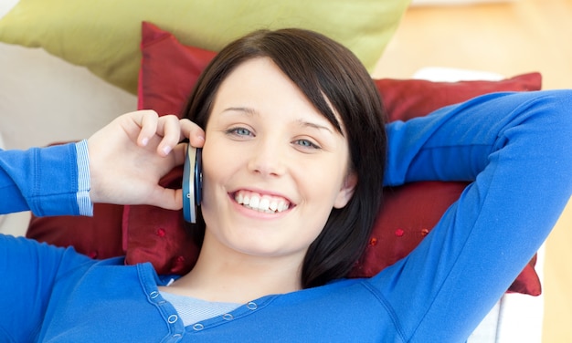 Encantadora menina adolescente falando no telefone, deitada em um sofá