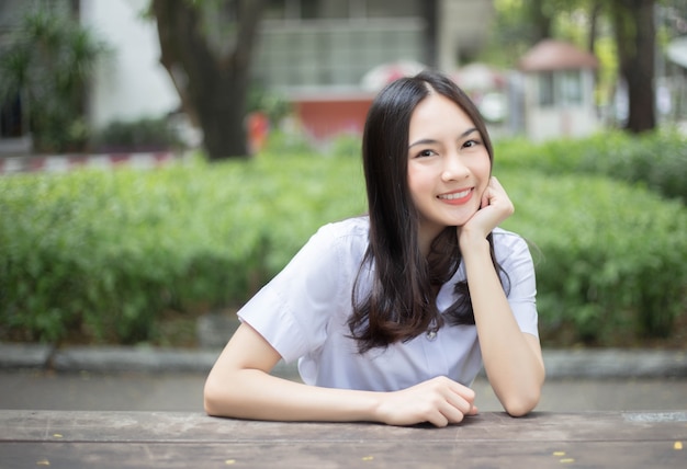 Encantadora menina asiática adolescente sorrindo em uniforme de estudante universitário