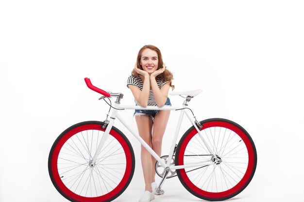 Foto encantadora modelo apoyándose en bicicleta posando