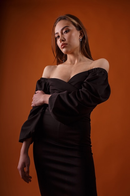 Encantadora modelo elegante con vestido negro posando. asiático, flaco, mujer joven, en, sexy, vestido de noche