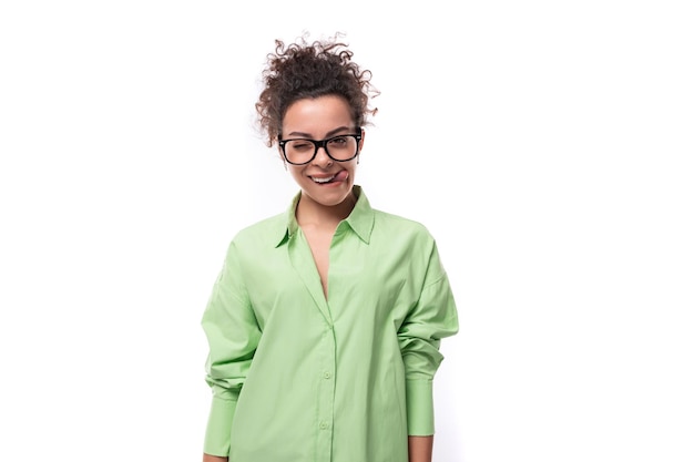 Encantadora modelo joven y delgada vestida con una camisa verde claro sobre un fondo blanco