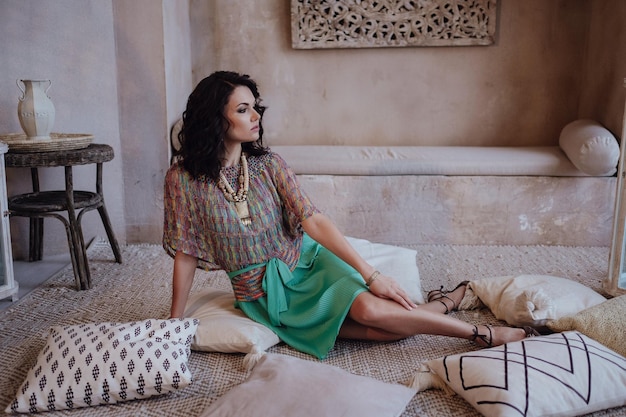 Encantadora modelo posando em um vestido vermelho durante suas férias para marrocos em seu riad em marrakech linda garota marroquina no quarto deserto