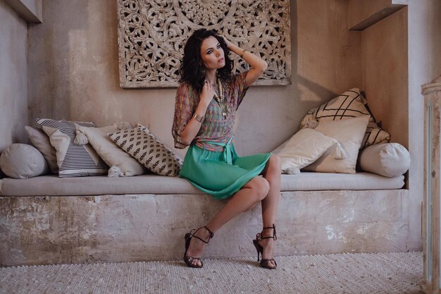 Encantadora modelo posando con un vestido rojo durante sus vacaciones en Marruecos en su riad en Marrakech Hermosa chica marroquí en la habitación del desierto