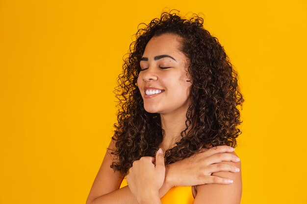 encantadora mujer afro con cabello rizado feliz con los ojos cerrados sonriendo.