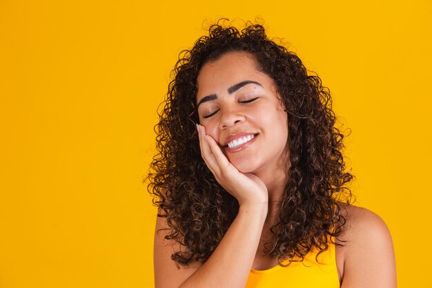 encantadora mujer afro con cabello rizado feliz con los ojos cerrados sonriendo.