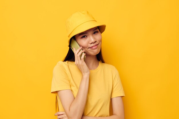 Encantadora mujer asiática joven hablando por teléfono posando fondo aislado de moda inalterado