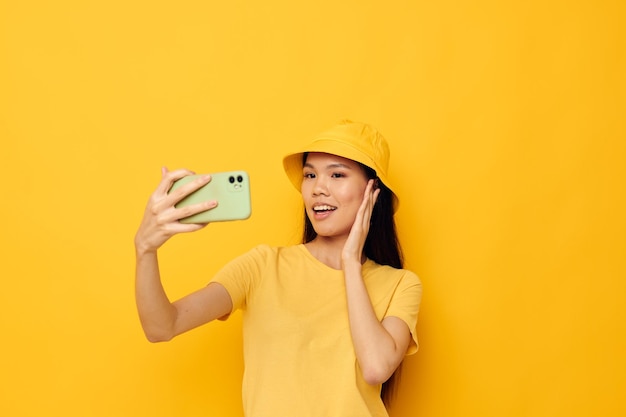 Encantadora mujer asiática joven hablando por teléfono posando fondo aislado de moda inalterado