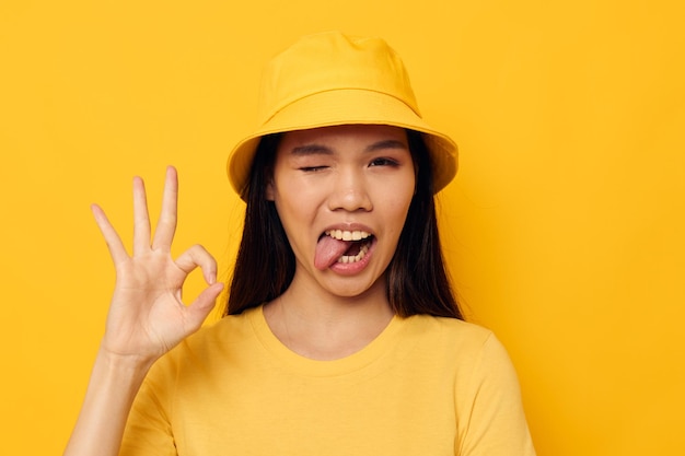 Encantadora mujer asiática joven con un sombrero amarillo posando emociones tiro monocromo