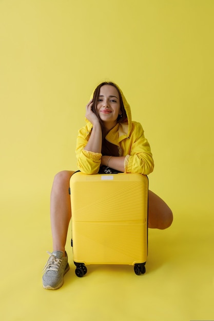 Encantadora mujer con bolsa de viaje posando en estudio