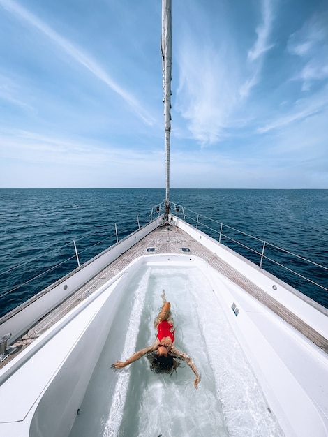 Foto una encantadora mujer delgada nada en la piscina ubicada en el yate