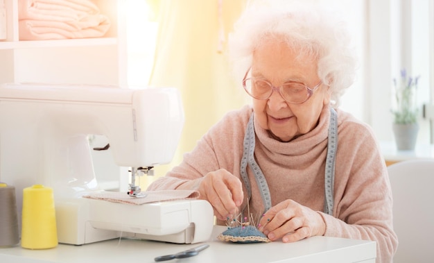 Encantadora mujer de edad cosiendo en el taller