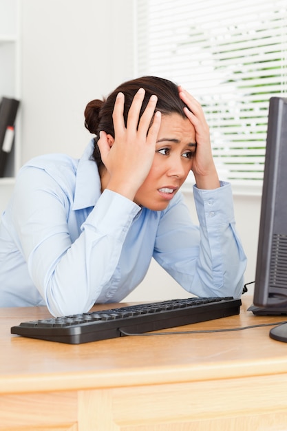 Foto encantadora mujer enojada mirando una pantalla de computadora mientras está sentada