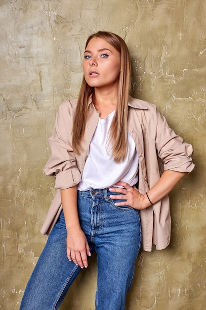 Encantadora mujer guapa en traje casual posando en estudio con fondo marrón