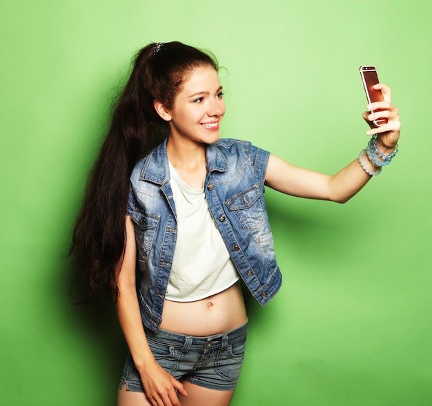 Encantadora mujer haciendo foto selfie en smartphone sobre fondo verde