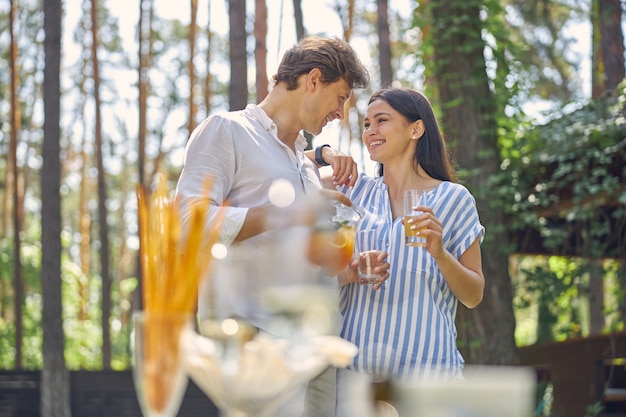 Encantadora mujer y hombre guapo sosteniendo un vaso con bebida fría al aire libre