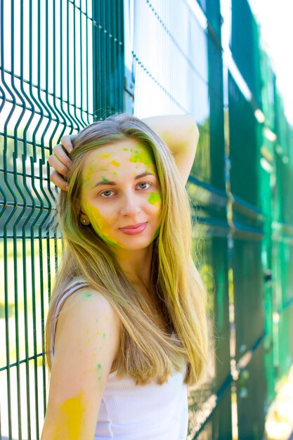 Encantadora mujer joven con polvo verde y amarillo Holi en su cara