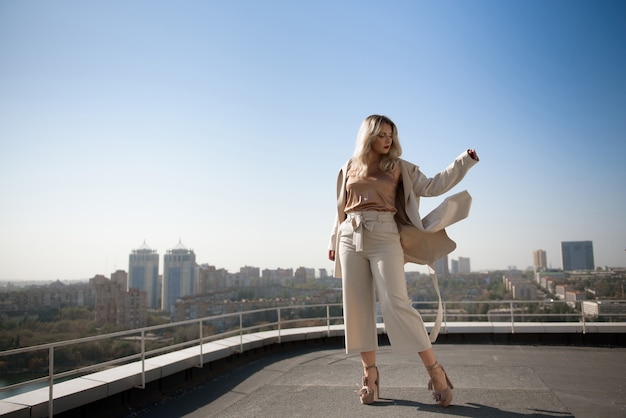 Encantadora mujer joven posando en la azotea del hotel con vistas a la ciudad.