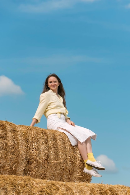 Encantadora mujer joven sentada en un pajar en la granja Cosecha de heno para el otoño Vacaciones en el campo