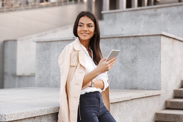 Encantadora mujer joven mediante teléfono móvil