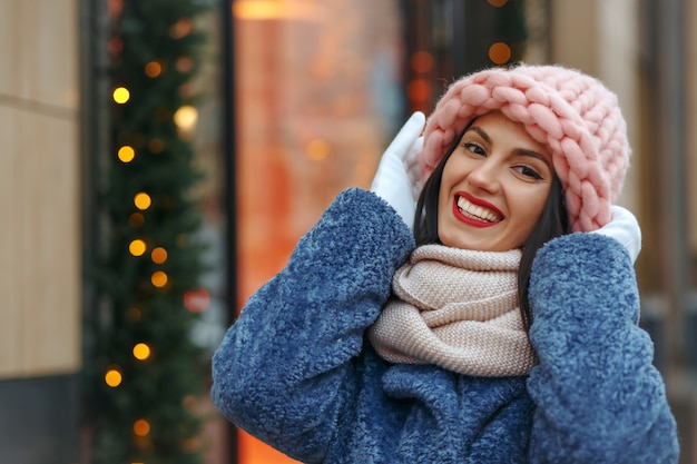 Foto encantadora mujer morena con abrigo caminando en la ciudad en invierno. espacio vacio