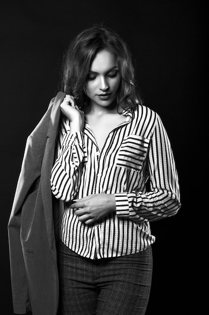 Encantadora mujer morena viste camisa y chaqueta de hombre en el estudio con una luz espectacular. Retrato en blanco y negro