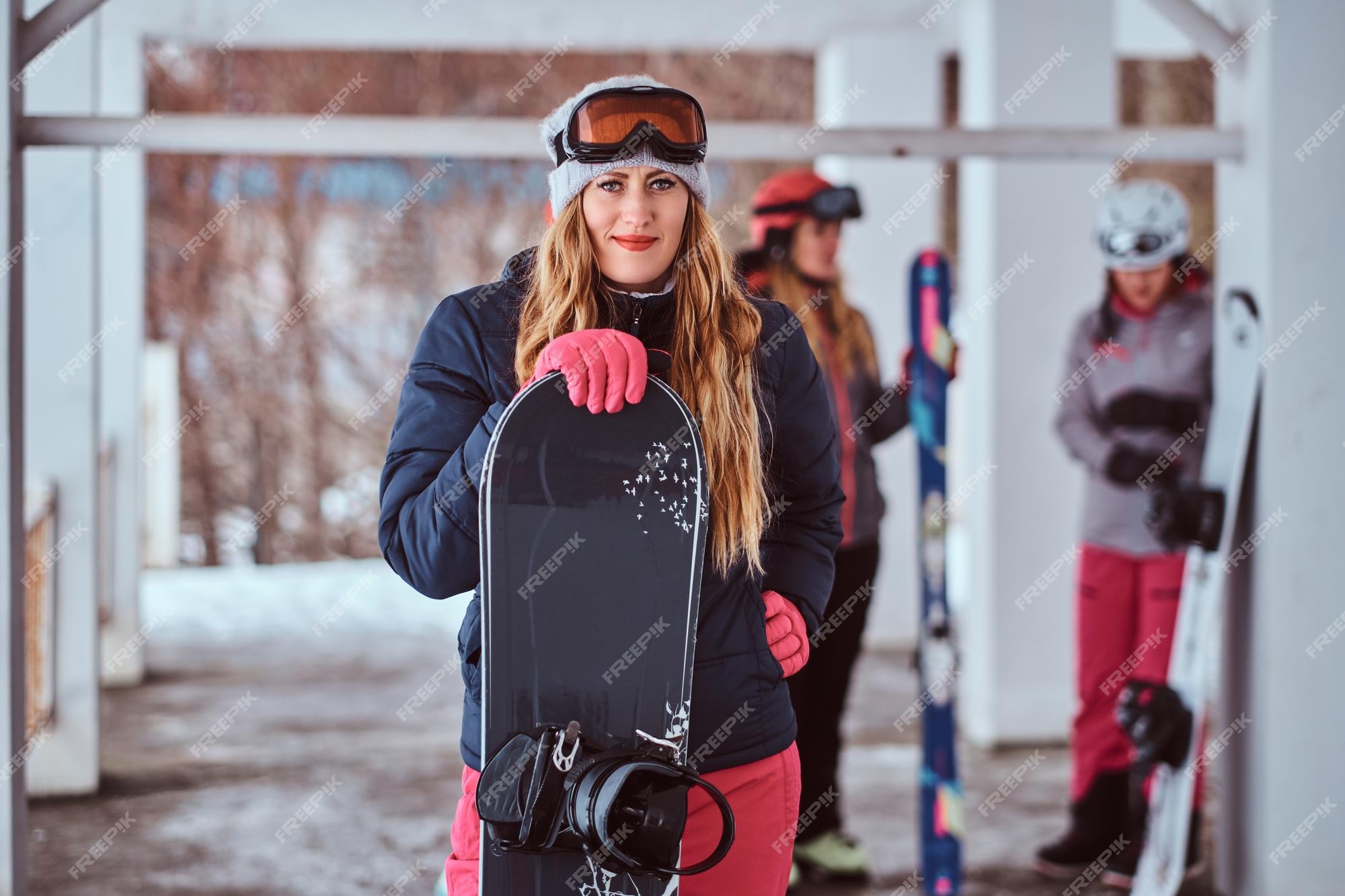 Encantadora mujer noruega ropa de abrigo y gafas con una tabla de snowboard en la estación de esquí de invierno Foto