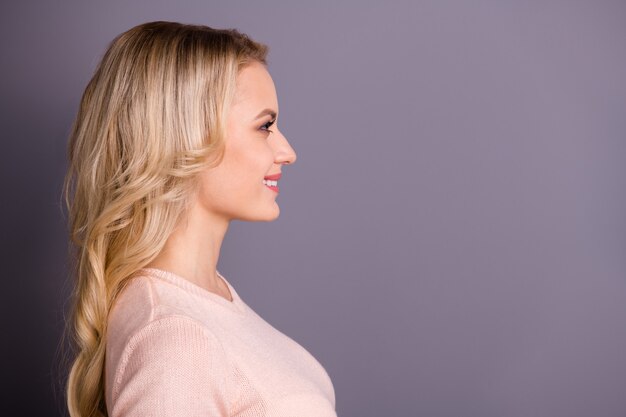 Encantadora mujer rubia posando contra la pared púrpura