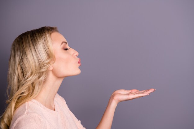 Encantadora mujer rubia posando contra la pared púrpura