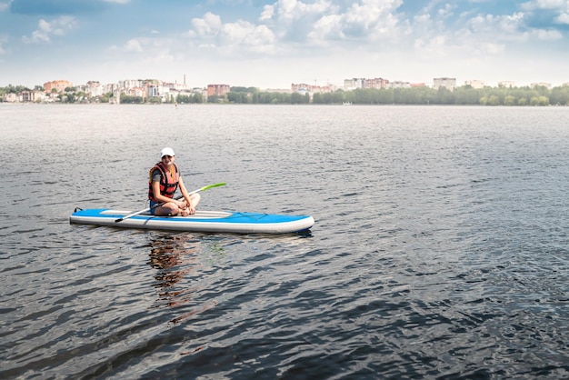 Encantadora mujer sonriente monta una tabla de remo alrededor del lago de la ciudad estilo de vida activo deporte y salud