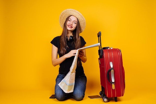 Una encantadora mujer sonriente con un sombrero de paja emprendió un viaje a otra ciudad con un mapa