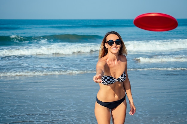 Encantadora mujer tocando un disco volador en la playa