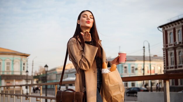 Encantadora mujer vestida con chaqueta beige está soplando un beso