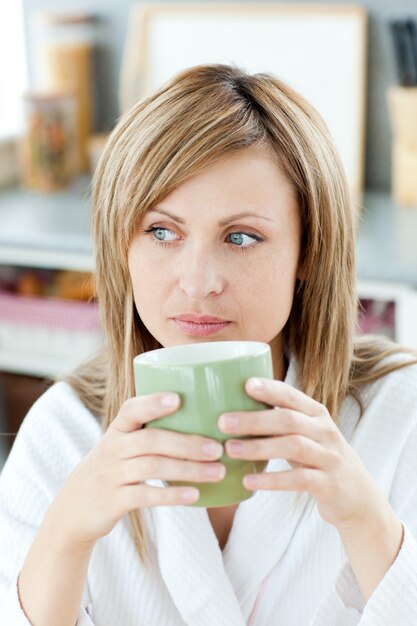 Encantadora mulher caucasiana loira curtindo o café na cozinha